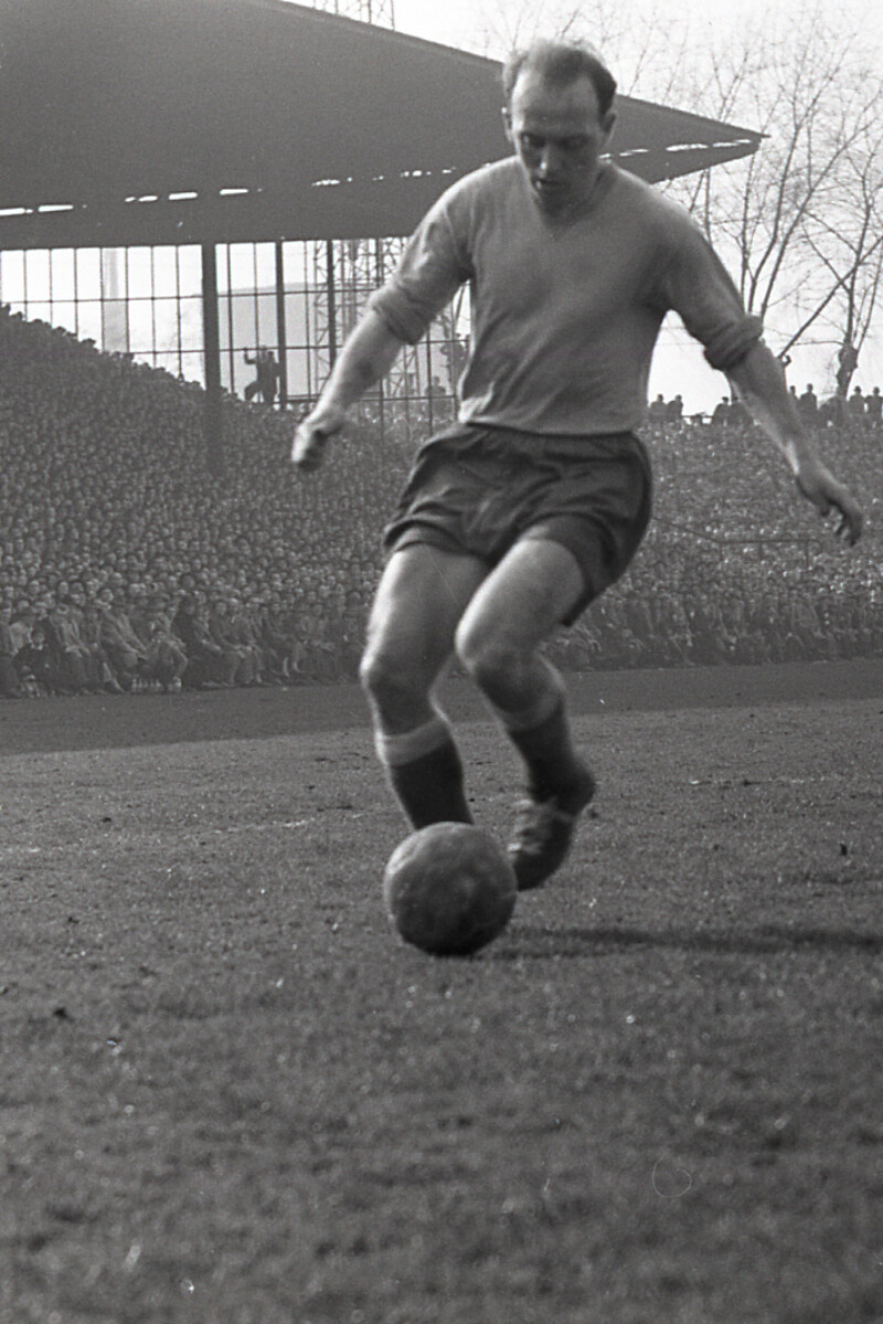 Der Fußballspieler Berni Klodt dribbelt mit dem Ball in der Kampfbahn Glückauf. Die überdachte Tribüne im Hintergrund ist voller Zuschauer.