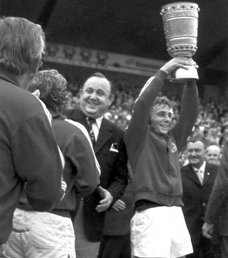 Der Kapitän des FC Schalke 04, Reinhard "Stan" Libuda, reißt den DFB-Pokal in einem vollbesetzten Stadion in die Höhe.