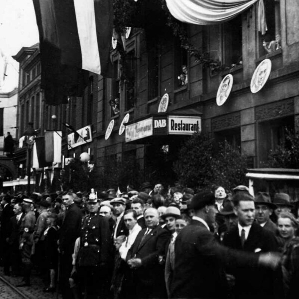 Eine Menschenmenge wartet am Schalker Markt vor der mit Fahnen geschmückten Kaiserhalle. An der Hausfassade hängen große Porträts der Spieler des FC Schalke 04.