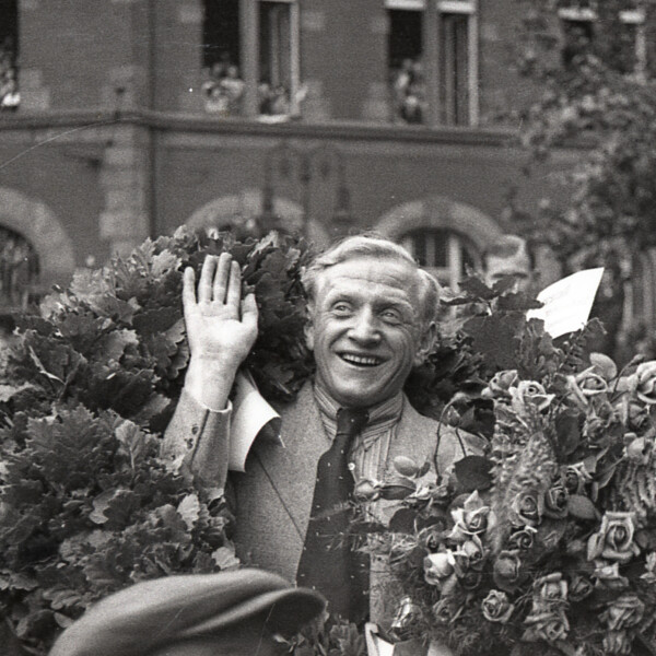 Fritz Szepan sitzt in einem offenen Wagen und wird bei der Feier zur Deutschen Meisterschaft 1939 durch Gelsenkirchen gefahren. Er lächelt und winkt den Zuschauern zu. Er trägt einen Siegeskranz um die Schultern und hält einen Blumenstrauß in der Hand.