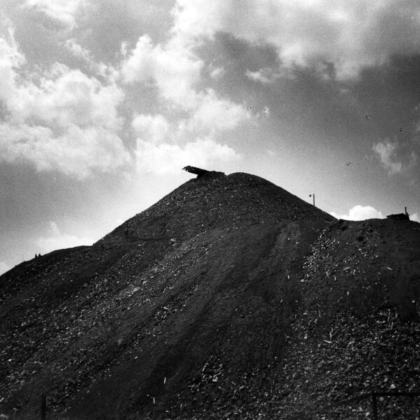 Die Fotografie zeigt eine Halde. Die Aufnahme wurde von unten aufgenommen. Die Halde wirkt massiv.
