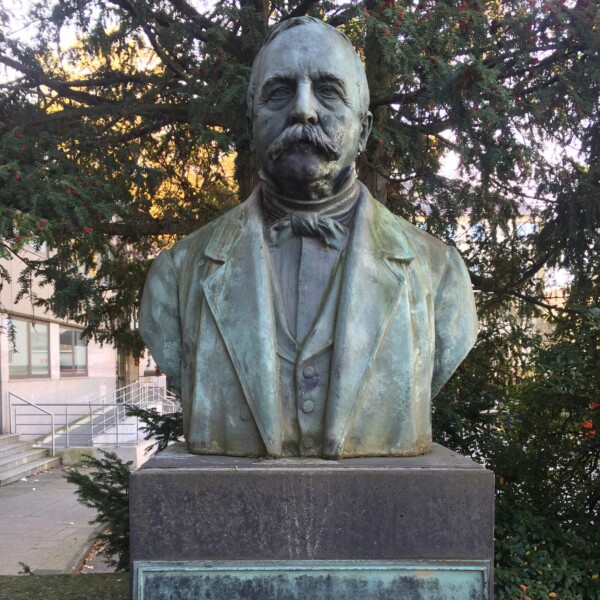 Nahaufnahme der Büste Friedrich Grillos auf dem Grilloplatz in Gelsenkirchen-Schalke. Auf dem Sockel ist ein Plakette mit der Aufschrift "Friedrich Grillo. Der Gründer der Schalker Industrie" angebracht.
