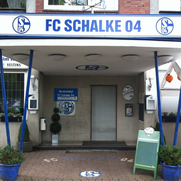 Heute ist der Eingang zum Vereinslokal "Bosch" an der Kampfbahn Glückauf in Schalke überdacht. Auf dem Dach ist über die ganze Breite angebracht. Auf dem Schild steht "FC Schalke 04".