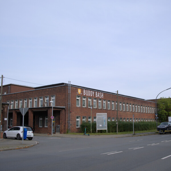 Ein zweigeschossiger Flachbau der ehemaligen Zeche Consolidation an der Gewerkenstraße in Schalke. An dessen Fassade die Aufschrift "Buddy Bash" angebracht ist.