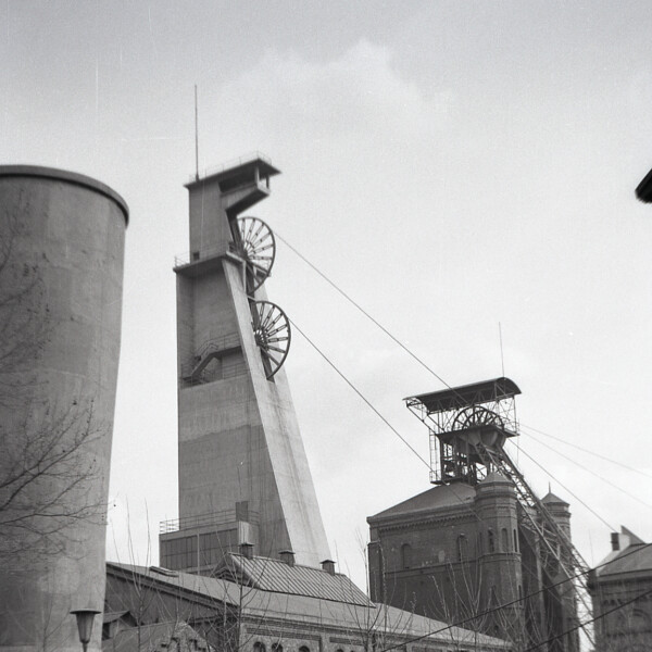 Der Förderturm über Schacht 4 ist mit Beton umhüllt. Über Schacht 3 steht noch das alte Fördergerüst. Die Schachtanlage ist von der Straße aufgenommen.