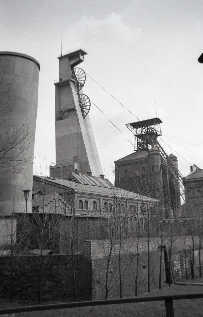 Der Förderturm über Schacht 4 ist mit Beton umhüllt. Über Schacht 3 steht noch das alte Fördergerüst. Die Schachtanlage ist von der Straße aufgenommen.