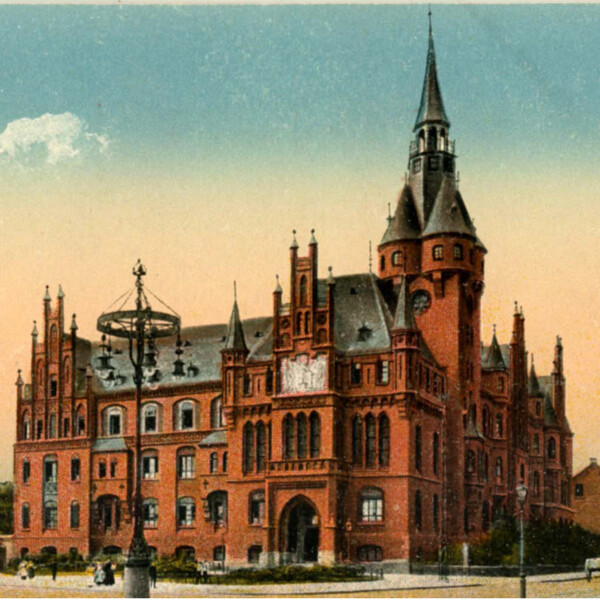 Postkartenansicht des alten Gelsenkirchener Rathauses am Machensplatz. Die Wände bestehen aus leuchtend-roten Backsteinen. Das Dach ist dunkelgrau gehalten.