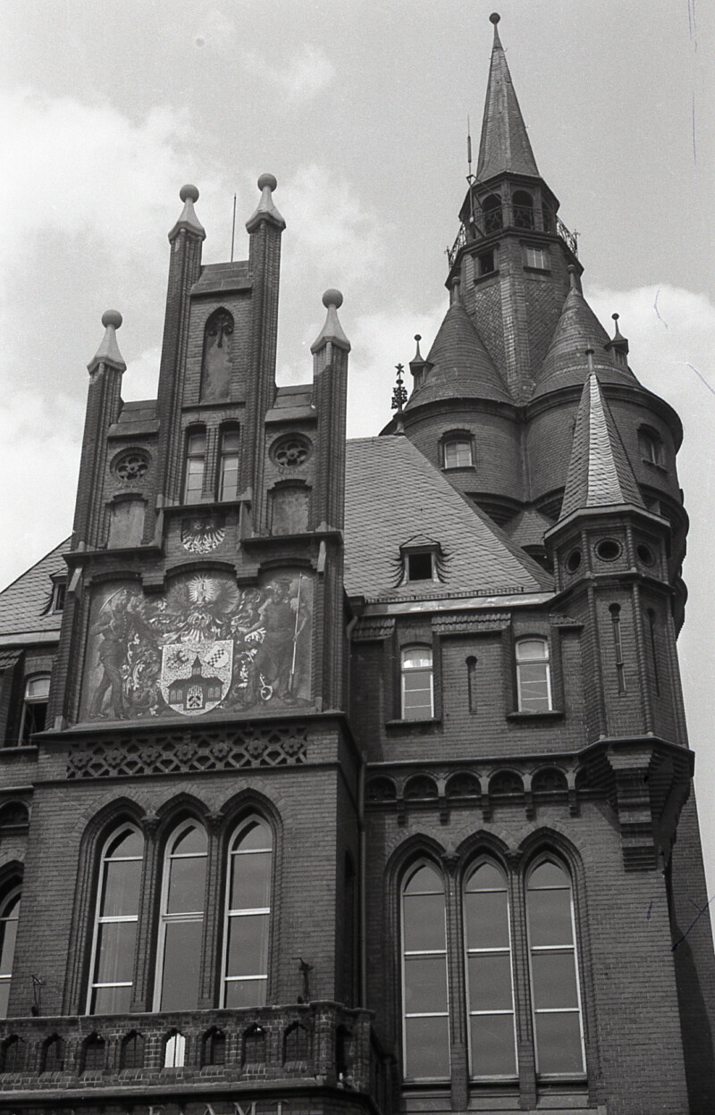 Ansicht des alten Rathauses am Machensplatz in Gelsenkirchen. Es verfügt über viele kleine Türmchen und Zinnen. Dadurch hat es ein mittelalterliches Aussehen.