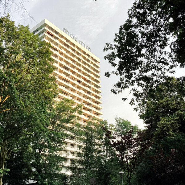 Ein weißes Hochhaus steht zwischen den Bäumen einer Parkanlagen. Auf dem Dach ist der Schriftzug "Maritim" zu sehen.
