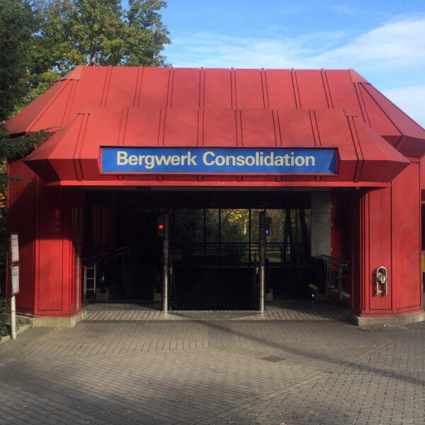 Ein rotes Eingangsgebäude zu einer U-Bahnhaltestelle. Über dem Eingang hängt ein Schild mit der Aufschrift "Bergwerk Consolidation".