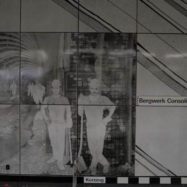 Ein Gemälde an der Wand einer U-Bahnstation zeigt Bergmänner bei der Arbeit in einem Tunnel, der sogenannten Strecke. Die zwei Arbeiter auf der rechten Bildseite blicken direkt rüber zum Betrachter.